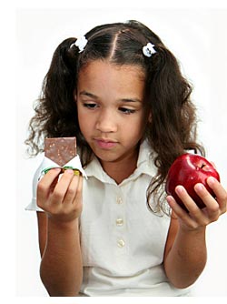 young girl choosing between candy bar and apple