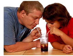 two people drinking from glass with separate straws