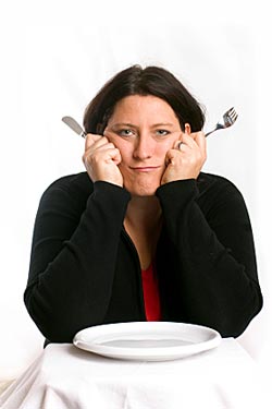 woman with a knife and fork but an empty plate