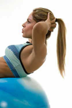 blond woman doing abdominal exercise on exercise ball