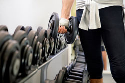 rack of dumbbells with person holding one dumbbell